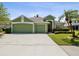 Green, three-car garage home featuring mature landscaping, a beige roof, and a concrete driveway at 1211 Penny Ct, Dunedin, FL 34698