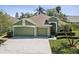 Charming single-story home featuring a well-manicured lawn, mature trees, and a three-car garage at 1211 Penny Ct, Dunedin, FL 34698
