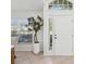 Bright front entry with a white door, a plant, a tile floor, and large front windows at 1211 Penny Ct, Dunedin, FL 34698