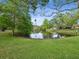 A scenic view of a serene pond surrounded by lush greenery and towering trees on a sunny day at 1211 Penny Ct, Dunedin, FL 34698