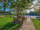 Entrance to Highlander Tennis Courts with a sign, pathway, and benches at 1211 Penny Ct, Dunedin, FL 34698