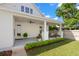 Covered back porch with outdoor seating, ceiling fans, and manicured lawn featuring verdant hedges and blooming flower pots at 1511 47Th N Ave, St Petersburg, FL 33703