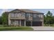 Two-story home with gray facade, columns, three-car garage, and well-manicured lawn at 15276 Rainbow Quartz St, Wimauma, FL 33598