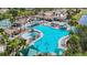 Aerial view of a large community pool with ample seating, umbrellas, and palm trees, adjacent to tennis courts at 2011 Halidom Way # 0, Sun City Center, FL 33573
