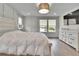 Bright primary bedroom with large window, dresser, light wood flooring, and modern decor at 2117 Lake Waters Pl, Lutz, FL 33558