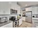 Modern kitchen featuring stainless steel appliances, gray countertops, sleek white cabinetry, and tile backsplash at 2117 Lake Waters Pl, Lutz, FL 33558