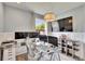 Well-lit office with modern glass desk, multiple monitors, and decorative pendant lighting fixture at 2117 Lake Waters Pl, Lutz, FL 33558