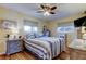 Bedroom with ceiling fan and soft natural light, featuring a striped bedspread and wood floors at 2131 Cedar Dr, Dunedin, FL 34698