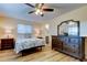 Cozy bedroom with wood-look floors, ceiling fan, and dark wood dresser at 2131 Cedar Dr, Dunedin, FL 34698