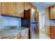 Close up of a stainless steel refrigerator, granite countertops, and wood cabinets at 2131 Cedar Dr, Dunedin, FL 34698