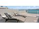 Cozy outdoor patio with modern lounge chairs offering tranquil water views and a glimpse of a distant bridge at 2171 E Vina Del Mar Blvd, St Pete Beach, FL 33706