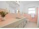 Bathroom features pink tile, a white vanity, ample natural light, and classic fixtures, creating a retro style at 2171 E Vina Del Mar Blvd, St Pete Beach, FL 33706