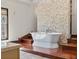 Elegant bathroom featuring a soaking tub with stone accent wall and wood floors at 2320 Coffee Pot Ne Blvd, St Petersburg, FL 33704