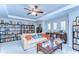 Bright living room featuring a comfortable sofa, ceiling fan, and custom bookshelves filled with books at 2515 Cross More St, Valrico, FL 33594