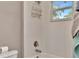 Bathroom with white tiled walls, a tub, shower head and fixture with a metal organizer at 3408 W Bay Ave, Tampa, FL 33611