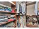 Organized walk-in closet featuring shelving with folded clothes, and hanging shirts and pants on rods at 3408 W Bay Ave, Tampa, FL 33611