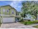 Two story home featuring an attached garage, well manicured lawn, and beautiful tree in the front yard at 3408 W Bay Ave, Tampa, FL 33611