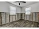 Bedroom featuring cinder block walls, two windows, ceiling fan, and old wood flooring at 512 79Th Ave, St Pete Beach, FL 33706