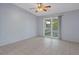 Bright, empty room with ceiling fan, tile flooring, and sliding glass doors to outdoor area at 5814 Silver Moon Ave, Tampa, FL 33625