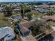 Stunning aerial view of a blue house with a pond, surrounded by lush trees and neighborhood charm at 8742 Bermuda Ln, Port Richey, FL 34668