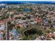 This aerial view shows the neighborhood and pond filled with algae, surrounded by lush green trees at 8742 Bermuda Ln, Port Richey, FL 34668