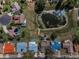 Aerial view shows homes with swimming pools, lush greenery, and a algae filled pond within the neighborhood at 8742 Bermuda Ln, Port Richey, FL 34668