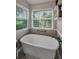 Bright bathroom featuring standalone tub, garden window with blinds, and modern black matte fixtures at 8742 Bermuda Ln, Port Richey, FL 34668