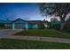 Charming light-blue house featuring a well-maintained lawn and a gray two-car garage at dusk at 8742 Bermuda Ln, Port Richey, FL 34668