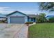 Charming light-blue house features a well-maintained lawn, brick path, and a gray two-car garage at 8742 Bermuda Ln, Port Richey, FL 34668