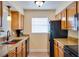 Galley kitchen featuring wood cabinets, granite counters, black appliances, and a window at 9001 Tudor Dr # H210, Tampa, FL 33615