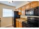 A bright kitchen with wood cabinets, granite counters, and black appliances at 9001 Tudor Dr # H210, Tampa, FL 33615
