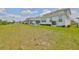 Expansive backyard with white exterior, covered patio, and lush greenery at 933 Signet Dr, Apollo Beach, FL 33572