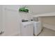 Bright laundry room with washer, dryer, wire shelf, and decorative plant on top of the shelf at 933 Signet Dr, Apollo Beach, FL 33572