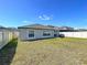 Spacious backyard featuring lush lawn, white fence, grill, and rear exterior at 9433 Channing Hill Dr, Sun City Center, FL 33573