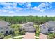 Aerial view of the home displaying a three-car garage, paver driveway, and surrounded by green trees at 10703 Morning Dew Way, Tampa, FL 33647