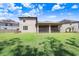 Expansive backyard view showcasing the manicured lawn, screened-in patio, and neighboring homes under a bright blue sky at 10703 Morning Dew Way, Tampa, FL 33647