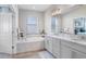 Bathroom featuring double vanity, framed mirror, and a separate soaking tub at 10703 Morning Dew Way, Tampa, FL 33647