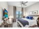 This bedroom features a stylish bed, a ceiling fan, a large window, and a cozy workspace with a desk and modern lamp at 10703 Morning Dew Way, Tampa, FL 33647