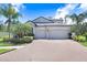 Stunning two-story home with a brick driveway, lush landscaping, and a spacious three-car garage at 10703 Morning Dew Way, Tampa, FL 33647