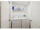 Functional laundry room with modern washer and dryer, complemented by a shelf for convenient storage at 21840 Waverly Shores Ln, Land O Lakes, FL 34637