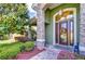 Charming front door with stone column and colorful wreath surrounded by colorful landscaping at 22338 Bartholdi Cir, Land O Lakes, FL 34639