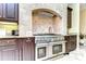 Gas range cooktop with custom tiled backsplash and dark wood cabinets with granite counters at 22338 Bartholdi Cir, Land O Lakes, FL 34639