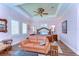 Spacious main bedroom with hardwood floors, tray ceiling, ceiling fan, and seating area with leather sofa at 22338 Bartholdi Cir, Land O Lakes, FL 34639