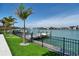 Beautiful backyard with lush grass, a dock, and waterfront views from behind a black fence at 25 Dolphin Dr, Treasure Island, FL 33706