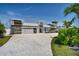Modern home featuring a two-car garage, decorative stone accents, a concrete driveway, and tropical landscaping at 25 Dolphin Dr, Treasure Island, FL 33706
