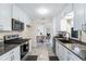 Updated kitchen with stainless steel appliances, white cabinets, and gray countertops open to dining room at 25337 Durango Ct, Punta Gorda, FL 33955