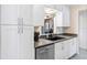Bright kitchen featuring white cabinetry, stainless steel dishwasher, and gray countertops at 25337 Durango Ct, Punta Gorda, FL 33955