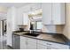Modern kitchen featuring white cabinetry, stainless steel dishwasher, and a window view to the living area at 25337 Durango Ct, Punta Gorda, FL 33955