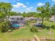 Aerial view of a pool and backyard with an outdoor pavilion, green grass, and a wooden pier at the pond at 3626 Lake Joyce Dr, Land O Lakes, FL 34639