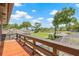 A scenic backyard view from a wooden deck, showcasing lush greenery, a screened pool, and a tranquil lake at 3626 Lake Joyce Dr, Land O Lakes, FL 34639